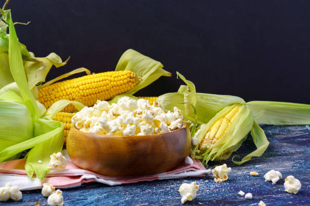 istock Tasty popcorn in a bowl on the table. Ears of fresh corn on a dark background. Copyspace 1338995559