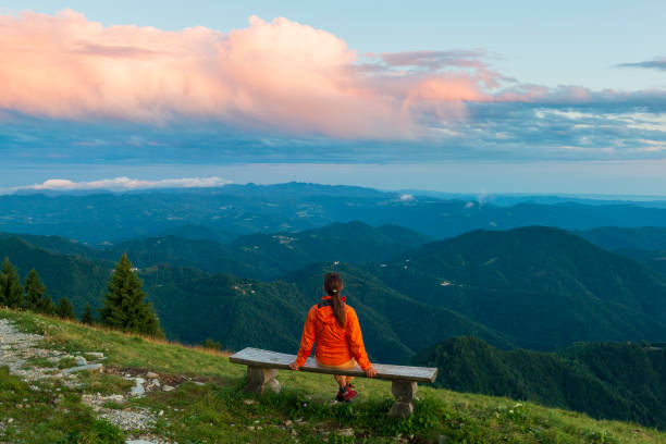 Girl on the wooden bench high in the mountains enjoy sunset stock photo