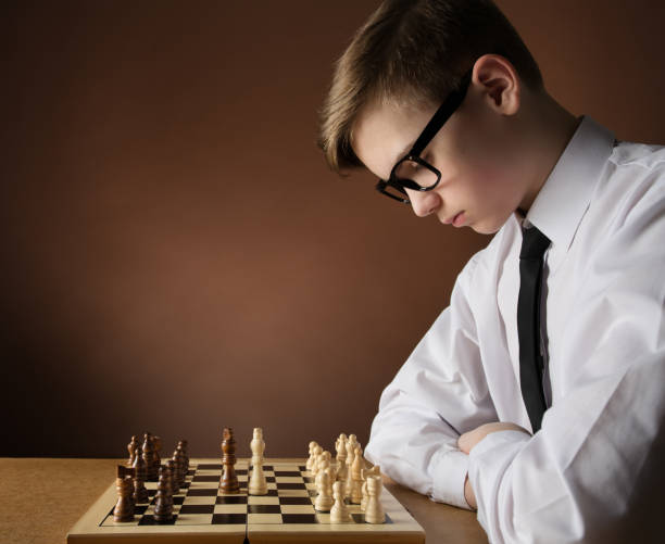 istock Chess Player Concentrate Thinking about Game Strategy at Chessboard. Young Boy playing board Game over Dark Brown Studio Background. Side view 1338995693