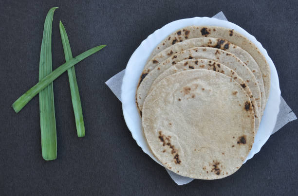 Top view of roti (chapati) on white plate over black background