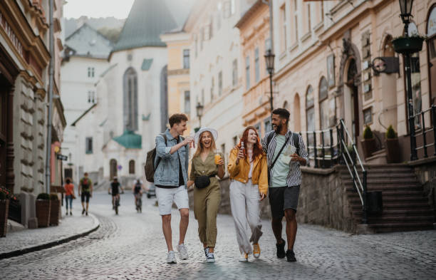 Front view of group of happy young people with drinks outdoors on street on town trip, laughing. A front view of group of happy young people with drinks outdoors on street on town trip, laughing. city break stock pictures, royalty-free photos & images