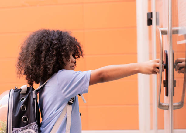 istock handsome little boy opens the school door 1338999373