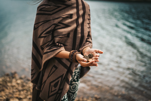 Hippie woman appreciating the nature, holding fir cones and watching the river