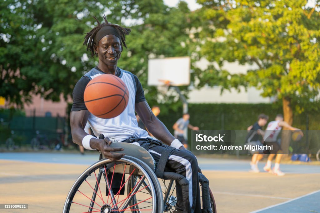 African man with a disability caused by polio playing basketball, champion athlete having disability in a wheelchair, concept of determination and mental toughness Athlete with Disabilities Stock Photo
