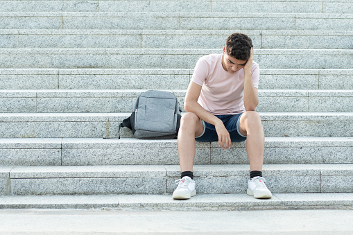 Adolescente hispano frustrado sentado en las escaleras photo