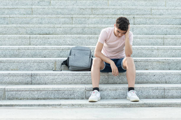 Frustrated hispanic teenager sitting on stairs Sad and frustrated hispanic teenager sitting on stairs and holding his head. Anxiety and depression in adolescence concept. low self esteem stock pictures, royalty-free photos & images