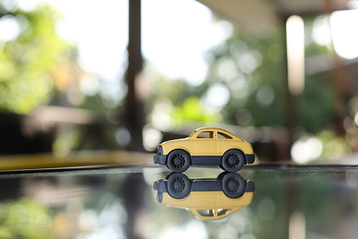 A yellow toy car gets reflected on a mirror