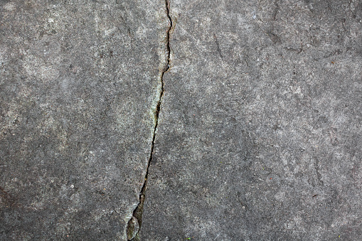 An old gray stone slab with a deep crack on a smooth surface.