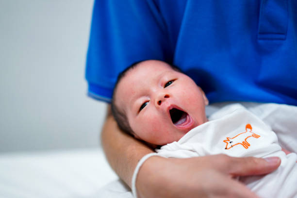 petite fille nouveau-née bâillant dans une main embrassante. - baby yawning asian ethnicity newborn photos et images de collection