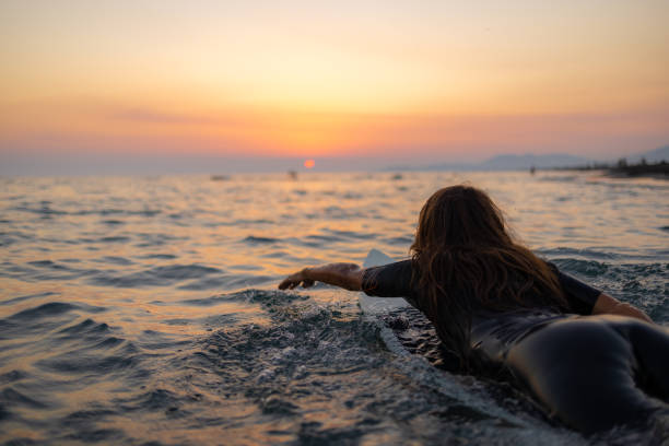 Rear view of a Caucasian women surfing while on a vacation stock photo