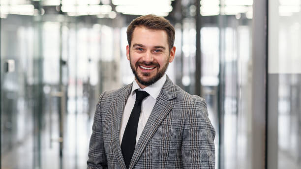 istock Front view of good-looking contented high-skilled 30-aged male office manager with beard which posing on camera in beautifully designeted with glass company corridor 1339014332