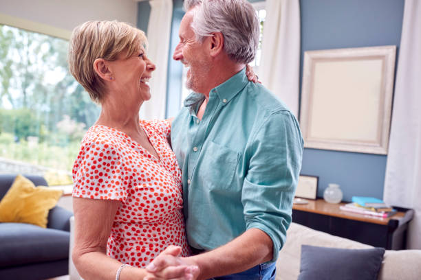 romantic senior retired couple dancing in lounge at home together - date night imagens e fotografias de stock