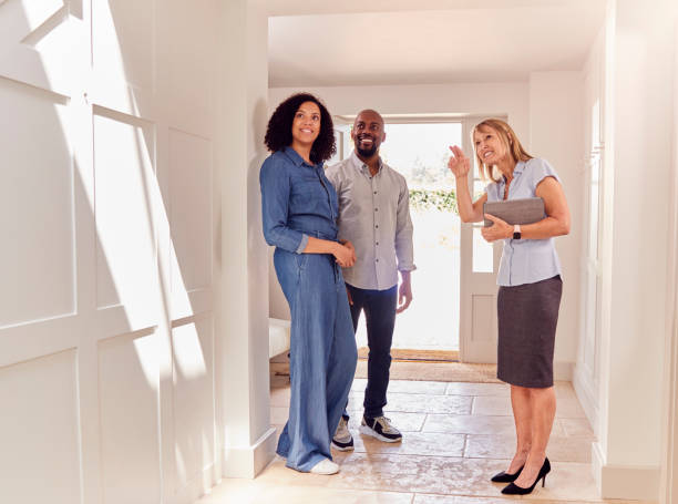 Couple Viewing Potential New Home With Female Real Estate Agent Couple Viewing Potential New Home With Female Real Estate Agent looking around stock pictures, royalty-free photos & images