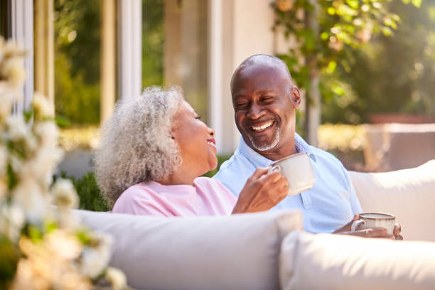 couple de retraités assis à l’extérieur à la maison en prenant un café le matin ensemble - couple cheerful happiness men photos et images de collection