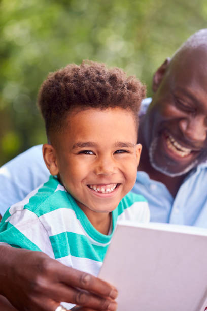istock Grandfather Sitting Outdoors With Grandson At Home Reading Book Together 1339017601