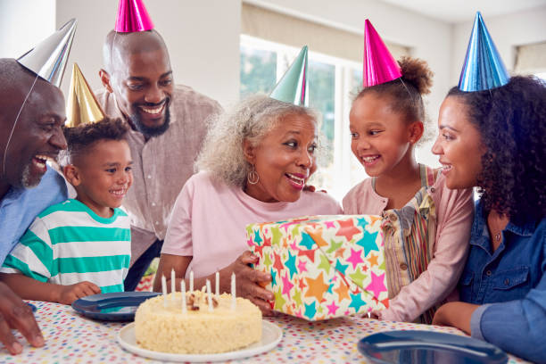 ケーキとパーティーで祖母の誕生日を祝う自宅のテーブルの周りのマルチジェネレーションファミ�リー - birthday family party cake ストックフォトと画像