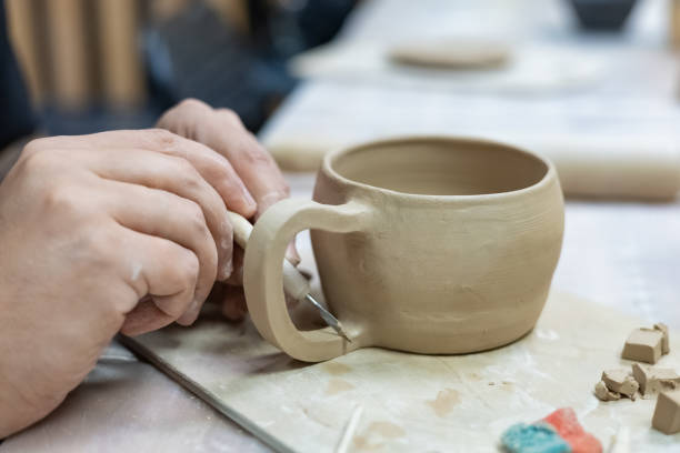 istock a ceramic artist processes the handle of a clay mug 1339018784