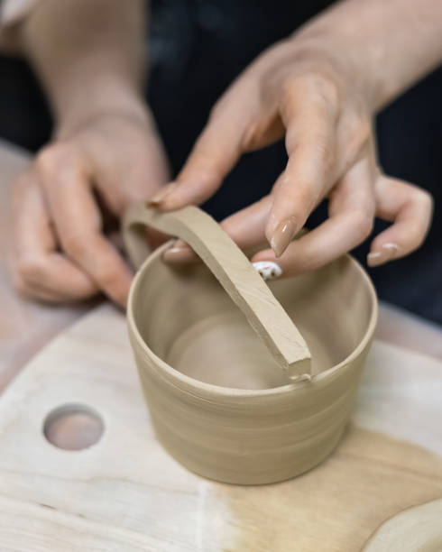 istock the potter's hands sculpt a handle on the blank of a clay mug 1339018811