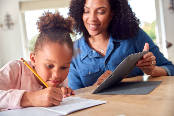 istock Mother Helping Daughter With Home Schooling Sitting At Table With Digital Tablet 1339018819