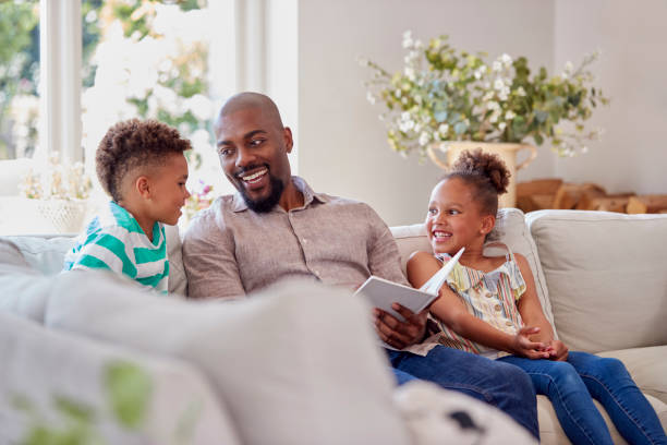 istock Father Sitting On Sofa With Children At Home Reading Book Together 1339018968