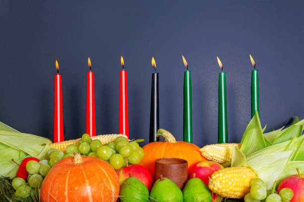 Kwanzaa Afro-American holiday. Corn, bowl and harvest. Kwanzaa Afro-American holiday with candles on dark background. Seven candles as symbol of principles of African Heritage. Pumpkin, corn, grapes, pears, apples and wooden bowl. angolan kwanza photos stock pictures, royalty-free photos & images