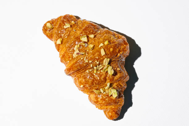 istock Sweet croissant with pistachio paste and nuts on a white plate. Hard light 1339020358