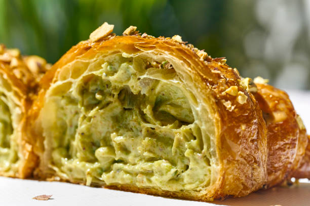 Sweet croissant with pistachio paste and nuts on a white plate. Hard light