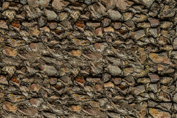stone wall old and weathered from brown cobblestones - color image solid brown bumpy imagens e fotografias de stock
