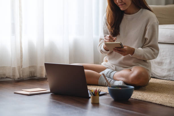 istock A woman writing and using laptop computer for working or studying online at home 1339023015