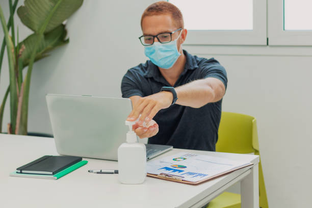 istock Young man putting on hand sanitizer in office 1339023173