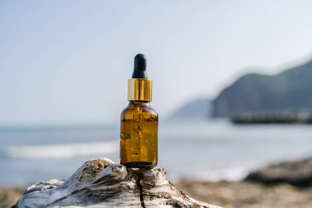 A bottle of serum on stones on a sea background. A bottle of serum on stones on a sea background. A great advertisement for mineral moisturizing cosmetics. scene scented stock pictures, royalty-free photos & images