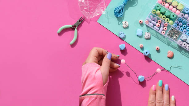 handmade jewelry. box with beads, hands with tools. making handmade jewelry for yourself or as self made gifts. flat lay, top view on split pink and mint green paper background - necklace jewelry bead homemade imagens e fotografias de stock