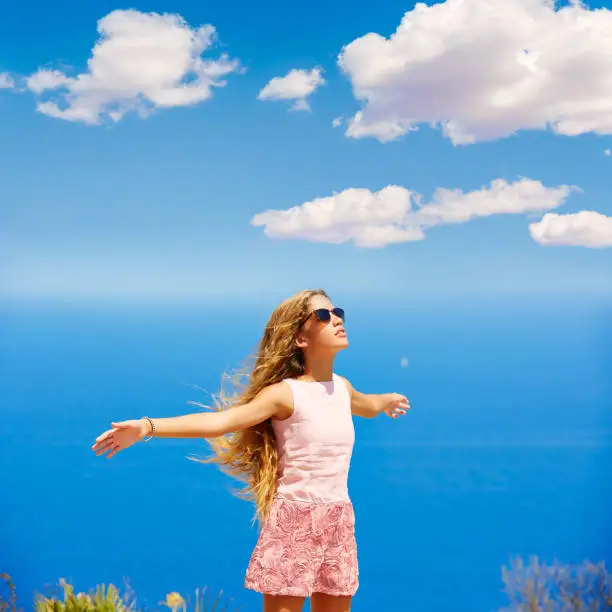Blond girl shaking hair on air at blue Mediterranean sea tourist in Spain open hands