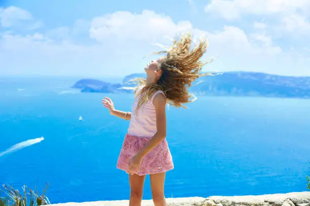 Blond girl shaking hair on air at blue Mediterranean sea tourist in Spain