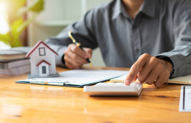 부동산 중개인 또는 보험 에이전트는 사무실 내에서 주택 모델 및 주택 부동산 판매 계약, 모기지 대출 승인 주택 대출 및 보험 개념과 함께 작동합니다. - 토지 관리인 뉴스 사진 이미지