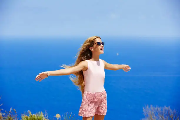 Blond girl shaking hair on air at blue Mediterranean sea tourist in Spain open hands