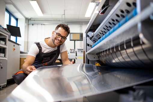 Print worker working on computer to plate machine in printing shop.