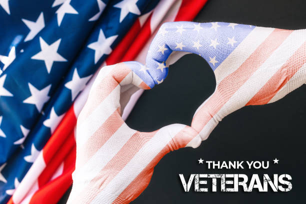 Veterans Day. Man's hands in gloves the color of the American flag, showing a heart gesture. Black background with flag. Close up. The concept of national American holidays Veterans Day. Man's hands in gloves the color of the American flag, showing a heart gesture. Black background with flag. Close up. The concept of national American holidays. thank you veterans day stock pictures, royalty-free photos & images