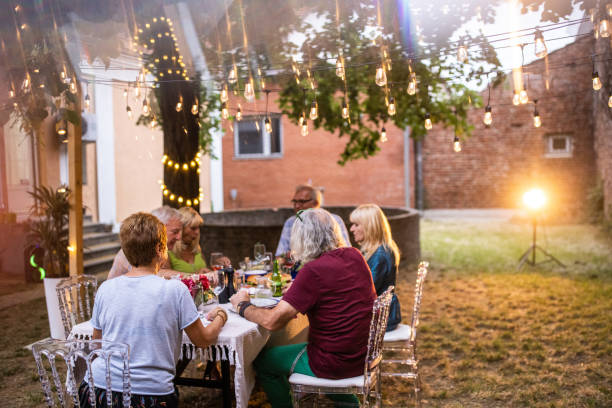 istock Senior people sitting at dining table and having fun conversation during garden party 1339035548