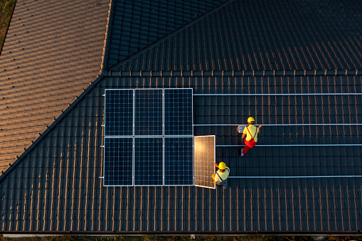 Professional Workers Installing Solar Panels On A Roof Of A House,Aerial View.