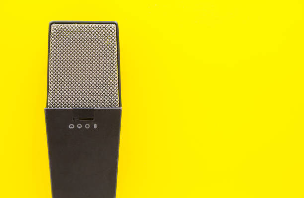 Old retro microphone on yellow background with copy space for text.