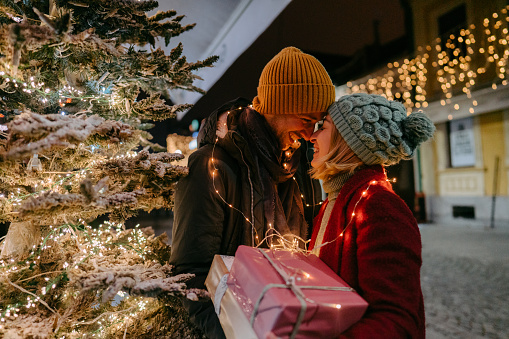 Photo of a romantic couple with Christmas presents outdoors