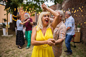 Senior couples spending fun time together dancing on party in backyard on summer day