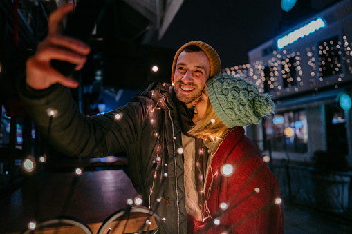 Photo of a romantic couple making selfie in the town during the Christmas holidays