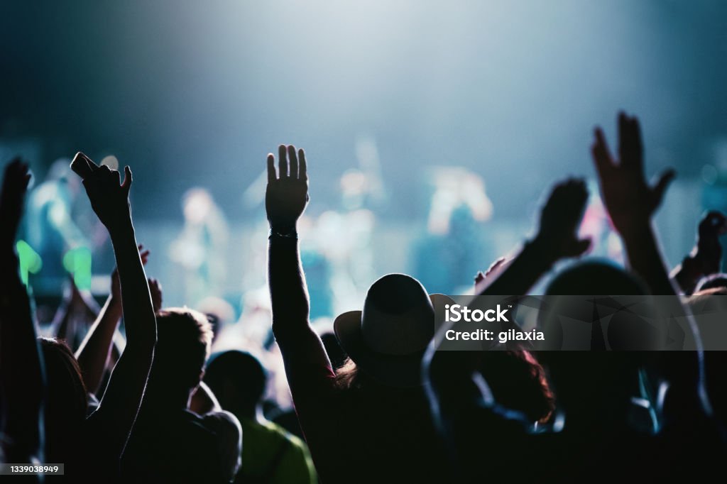 Rave party silhouettes. Rear view of large group of people enjoying a concert performance. There are many hands applauding and taping the show.
Silhouettes have been significantly liquified. Music Festival Stock Photo
