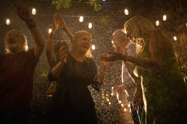 Senior people dancing on party while it's raining at night