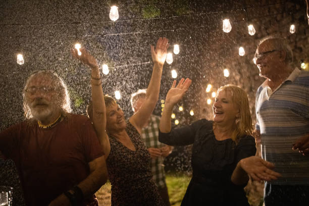 istock Senior friends dancing and having fun at backyard while it's raining at night 1339040510