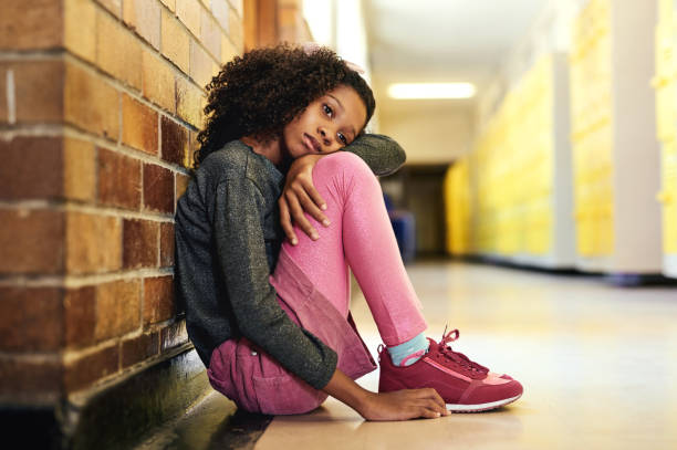 Full length shot of a young girl sitting alone in the hallway at school and feeling depressed I feel so alone at school one girl only stock pictures, royalty-free photos & images