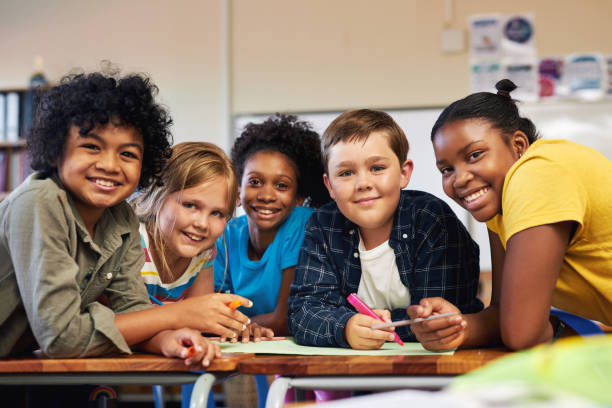 shot of a diverse group of children huddled together and colouring in their classroom at school - child school children elementary student group of people imagens e fotografias de stock