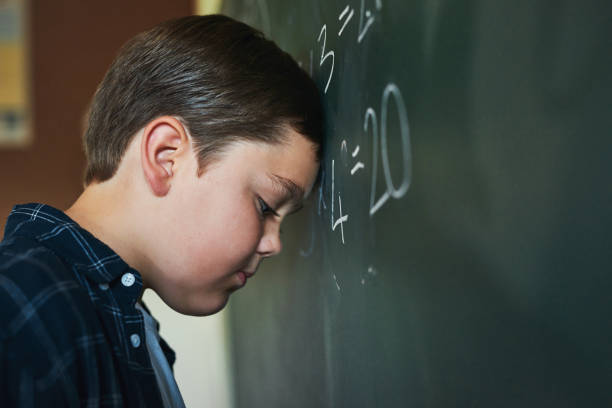 istock Shot of a young boy standing and feeling depressed while trying to answer a question on the blackboard at school 1339040626